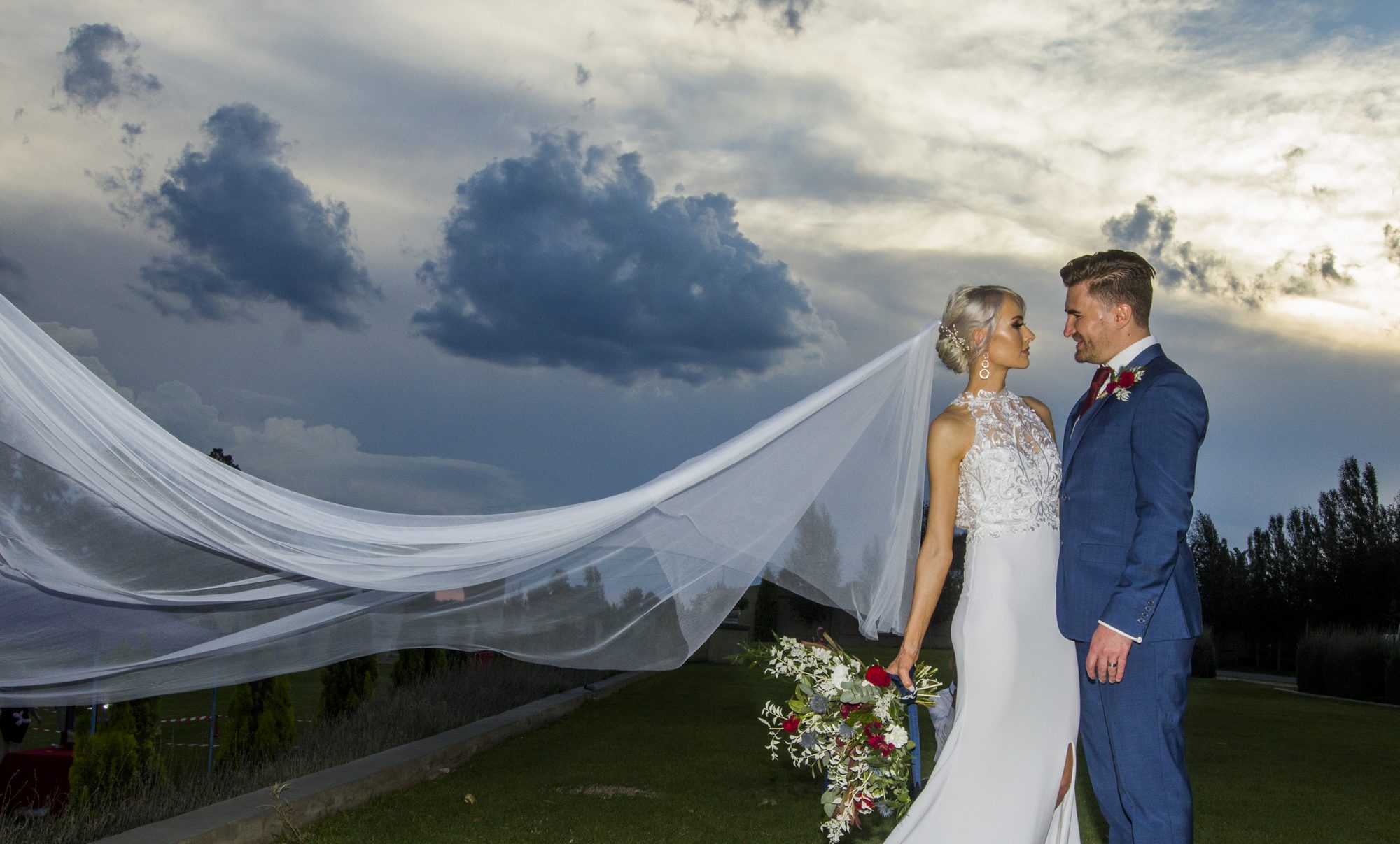 Bride and groom with flowing veil at sunset